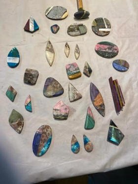 A table covered with polished mineral slabs and cabochons of various colors